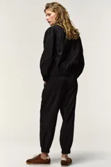 Pantalón negro de tiro medio con acabado brillante, cintura elástica ajustable con cordones y puños elásticos en los tobillos.