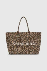 Tote bag de lona con estampado animal print de leopardo en tonos marrones y negros. Presenta el logo de la marca ANINE BING estampado en color blanco en la parte frontal y doble asa superior.