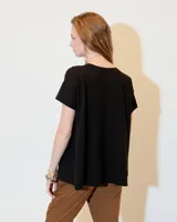 Remera blanca de jersey flama 100% algodón, de línea A y fit relajado, con escote redondo a la base, manga corta y recortes a los costados, tanto en delantero como en espalda.