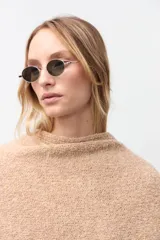 Ruana abierta de tejido de punto en color beige, con diseño holgado y bordes acanalados.