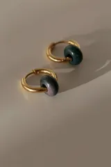 Par de aros tipo argolla dorados de acero quirúrgico, con una piedra natural de color gris translúcido colgando de cada uno.