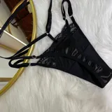 Set de lencería de cuatro piezas en color negro, compuesto por un bralette de encaje, tanga regulable, portaligas y liga para pierna. Diseño con detalles de tiras y encaje.