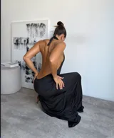 Vestido largo negro con escote halter profundo, diseño cruzado en la cintura y tajo lateral pronunciado en la falda.