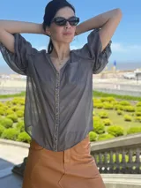 Camisa azul marino de gasa, con escote en V, mangas cortas abullonadas y detalle de piedras azules en el frente.