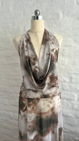 Vestido largo de microtul con estampado abstracto en tonos marrones y blancos, escote halter pronunciado, espalda descubierta y aberturas laterales en la cintura.