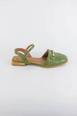 Sandalia de cuero verde con punta cerrada, detalle de flecos y aplicación metálica dorada en el empeine, y tira ajustable al tobillo con hebilla.