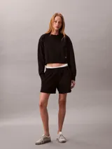Buzo cropped de cuello redondo, manga larga con puños acanalados y dobladillo con punto canalé. Presenta un diseño corto y una pequeña insignia con el logotipo de Calvin Klein en el lateral.