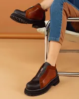 Botinetas de cuero combinadas en color negro y marrón, con diseño de paneles, cierre frontal y suela track dentada.