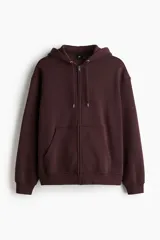 Campera con capucha de felpa color marrón oscuro (vino/borgoña), con interior cepillado suave. Presenta hombros caídos, cierre frontal, cordón para ajustar la capucha y bolsillos canguro delanteros. Puños y bajo terminados en punto acanalado.