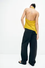 Jean de tiro alto y estilo baggy color negro, confeccionado en denim de algodón rígido, con diseño de cinco bolsillos, cierre de cremallera y botón metálico, y perneras amplias de corte holgado.
