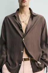 Camisa de corte relajado confeccionada en tejido fluido con mezcla de cupro, de manga larga con puños abotonados y cierre frontal de botones.