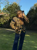 Saco corto de tejido de punto con diseño a rayas en tonos negro y amarillo, cuello destacado y cierre frontal con botones de nácar.