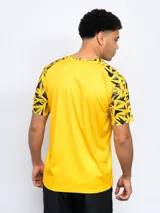 Remera deportiva de hombre, color negro, con cuello redondo y mangas cortas con estampado geométrico en amarillo y gris. Lleva el escudo de Peñarol en el pecho.