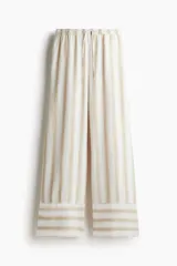 Pantalón de corte holgado confeccionado en mezcla de lino y viscosa, con diseño de rayas verticales. Presenta cintura elástica con cordón de ajuste y piernas amplias con detalle de franjas horizontales en el ruedo.