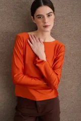 Remera de manga larga en color azul, con cuello bote y diseño ajustado al cuerpo. Presenta un acabado de borde sin costuras en el cuello y puños con abertura lateral.