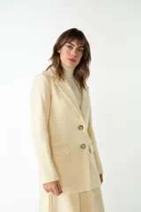 Blazer largo color crema con cuello solapa, bolsillos con solapa y forro interior combinado a tono. Confeccionado en lana fina sin teñir.