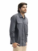 Camisa azul marino de manga larga confeccionada en algodón. Tiene cuello clásico, dos bolsillos frontales con tapa y velcro, abertura en la espalda con red interna y manga remangable con botón para fijar.