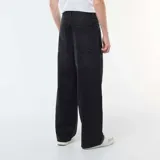 Pantalón de jean estilo baggy, de corte holgado y tiro medio, en color negro con efecto lavado. Cuenta con diseño de cinco bolsillos y cierre frontal con botón y cremallera.
