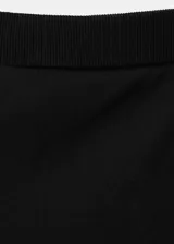 Pantalón de punto fino color negro, de diseño recto y tiro medio, con falda corta superpuesta integrada.