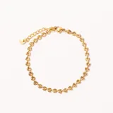 Pulsera dorada con eslabones en forma de corazón, cierre de mosquetón y cadena de extensión con dije circular.