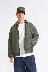 Campera Quiksilver modelo Milo para hombre, de color verde con textura en relieve y cuello camisero en contraste de color tostado. Cuenta con cierre frontal entero, bolsillos laterales ribeteados, puños y dobladillo inferior elásticos.