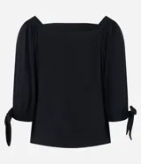 Blusa negra de viscosa con escote off-shoulder, mangas 3/4 con elásticos y lazos en los puños.