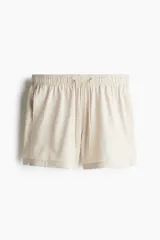 Short de baño de sirsaca con diseño a rayas verticales en tonos beige y blanco. Cuenta con cintura elástica con cordón ajustable, bolsillos laterales, bolsillo trasero con cierre autoadherente y suspensor interior de malla.