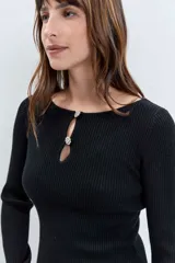 Sweater de punto acanalado color negro, de corte ajustado y manga larga. Presenta un escote redondo con una abertura frontal tipo gota decorada con botones joya.