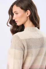 Buzo de tejido de punto con diseño de rayas horizontales en tonos neutros, beige y detalles en rosa y gris. Presenta cuello redondo, mangas largas y terminaciones en rib acanalado en puños y ruedo. Incluye una pequeña etiqueta de cuero sintético en el lateral inferior.
