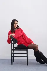 Vestido corto rojo con estampado floral, escote redondo, mangas largas con elástico en los puños, detalle de nudo drapeado en la cintura y escote en V pronunciado en la espalda.