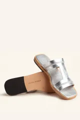 Sandalia plana de cuero color marrón, con tiras anchas y costuras blancas a la vista. Tiene punta cuadrada y un pequeño taco de 2 cm.