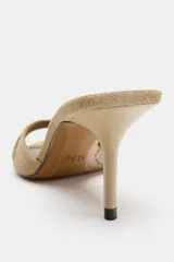 Sandalia de tacón destalonada estilo mule en piel, de color beige, con tira ancha delantera y tacón alto fino.