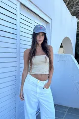 Top strapless color beige, de corte crop y confeccionado en tejido de punto.