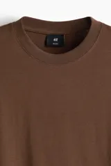 Remera de algodón color marrón, con cuello redondo y diseño de corte relajado con hombros caídos.