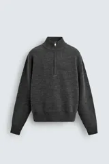 Jersey de punto de corte regular, color gris oscuro, con cuello subido y cierre frontal de cremallera. Presenta mangas largas y acabados en rib en puños y ruedo.