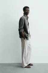 Sobrecamisa de hombre, color verde militar, con cuello solapa, manga larga y cierre frontal de botonadura. Presenta un bolsillo de plastrón en el pecho y bolsillos laterales en la cadera. El tejido tiene un efecto lavado.