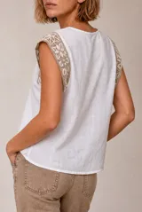 Blusa de lino color beige sin mangas, con cuello redondo y detalles de crochet en los hombros.