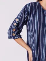 Blusa de algodón con diseño de rayas verticales en tonos azul, rosado y amarillo, escote en V con botones de madera, y mangas cortas con detalles de botones en los laterales.