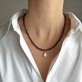 Collar de cuentas de piedra Ojo de Buey de 4 mm con un dije central de perla de río natural y detalles metálicos con baño de oro.