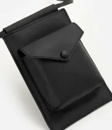 Billetera crossbody de poliuretano color negro, de diseño compacto y moderno con compartimento principal y bolsillo frontal con solapa y cierre a presión. Cuenta con asa larga para uso cruzado.