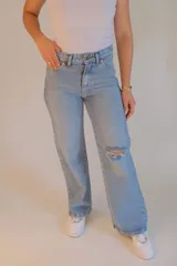 Jean celeste de tiro alto, corte wide leg y rotura en la rodilla.