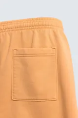 Bermuda de corte relajado confeccionada en tejido de algodón con interior de rizo. Presenta cintura elástica con cordón ajustable, bolsillos laterales, un bolsillo trasero de plastrón y bajo con acabado irregular con efecto lavado.