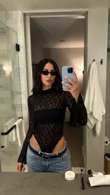 Body de encaje negro con cuello alto, mangas largas y diseño cavado, acompañado de un bandeau negro interno.