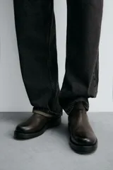 Bota de cuero con acabado abatanado, diseño de caña media, horma redonda y suela de goma con volumen a contraste.