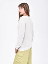 Buzo tejido de punto color beige, con escote en V y mangas largas holgadas.