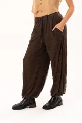 Pantalón tipo babucha de encaje color chocolate, con forro interior, cintura regulable y elásticos en los tobillos que generan una silueta abuchonada.