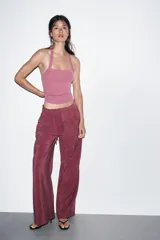 Pantalón de tiro alto color bordó, de corte ancho y pierna recta, con pinzas frontales y lazada ajustable en la cintura. El tejido presenta un acabado satinado o ligeramente arrugado.