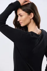 Buzo tejido liso de manga larga con cuello redondo, confeccionado en algodón de tejido grueso. Presenta bordes acanalados en el cuello, los puños y la cintura, con un pequeño detalle de placa metálica en el lateral inferior.