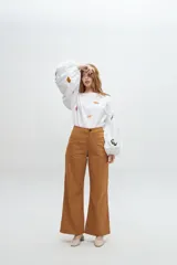 Blusa color arena de algodón con escote a la base y mangas abullonadas. Presenta bordados artesanales de motivos marinos en tonos naranja y azul.