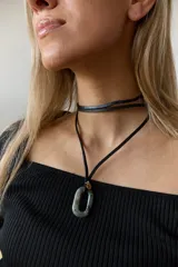 Collar con tiento negro y dije de piedra natural ovalada en tonos grises y azules.